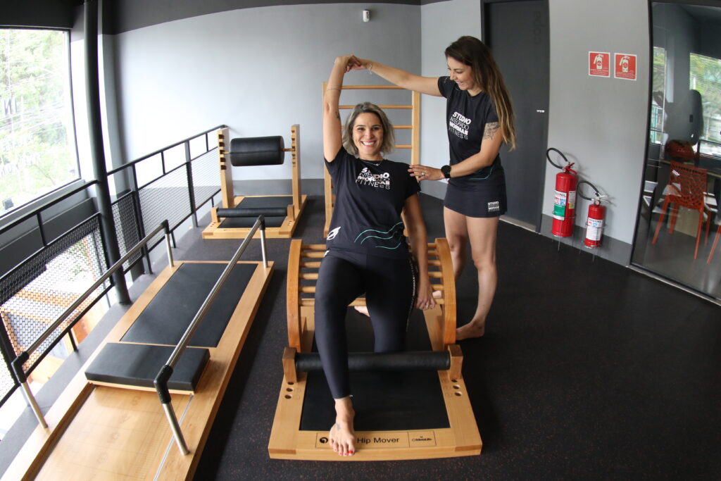 Professora de pilates auxiliando aluna na execução de um exercício no Studio Pilates