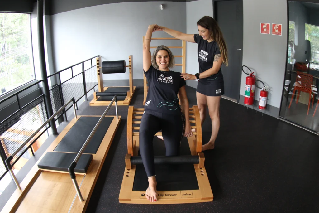 Professora de pilates auxiliando aluna na execução de um exercício no Studio Pilates