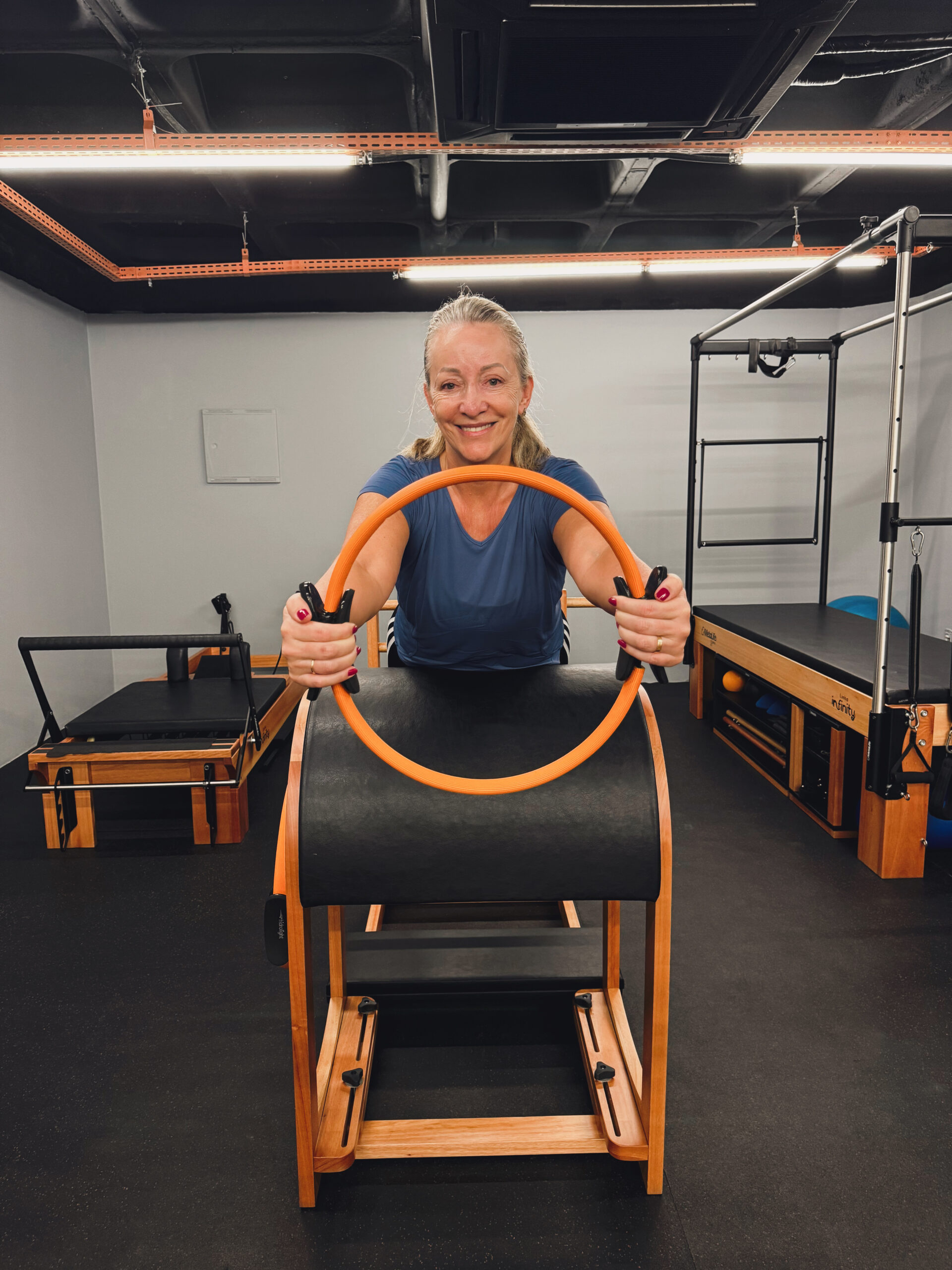 Aluna sorrindo enquanto faz um exercício de Pilates no Studio Mormaii