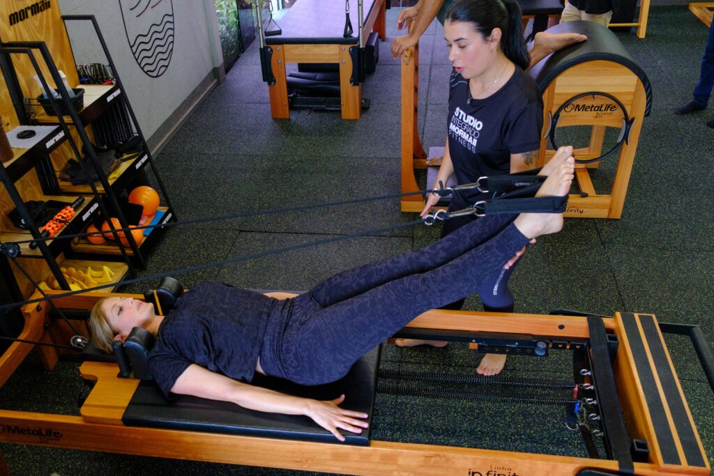 aluna sendo auxiliada pela treinadora no pilates do studio mormaii